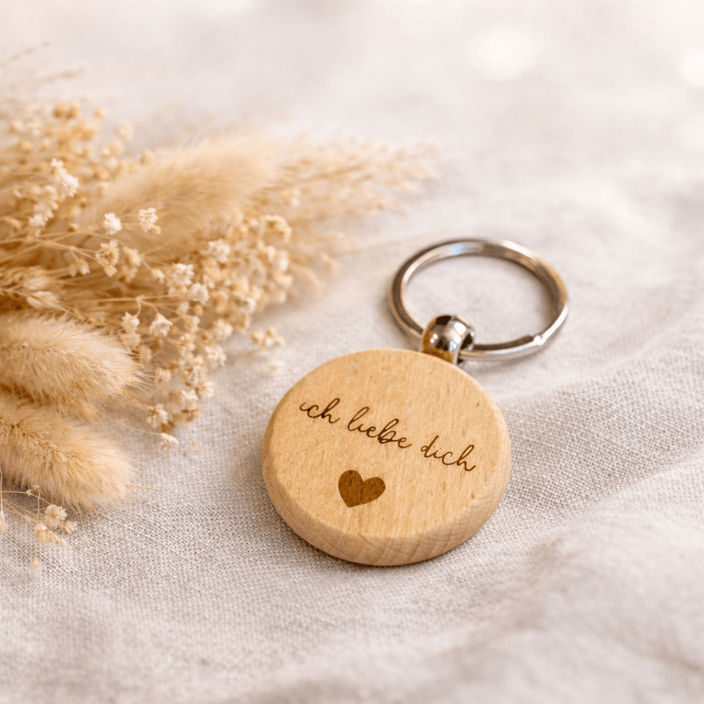 Ein runder Holz Schlüsselanhänger auf einem schön dekorierten Tisch mit der Aufschrift Ich liebe dich und einem Herz-Symbol, passend zum Valentinstag